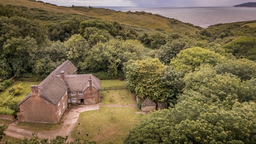 An aerial view of St Gabriel’s Cottages, including Beech Cottage, and the nearby coast, Dorset